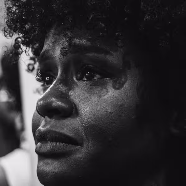 A closeup of a woman with curly hair crying and looking distressed.