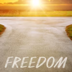 Healing for the heart and freedom for the soul are represented by the word freedom painted into the road with a sunrise in background.